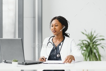 � happy smiling african american female doctor or nurse with headset and laptop having conference or video call at hospital