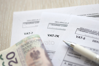 AT-7K, VAT-7 form on accountant table with pen and polish zloty money bills close up