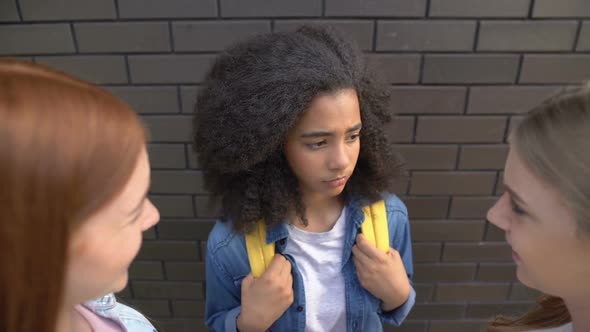 Female Teenagers Looking at Younger Black Schoolmate, Bullying Problem, Abuse