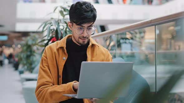 Young Indian Man Looking at Laptop Screen Checking Email Smiling Enjoying Free Time Browsing Web