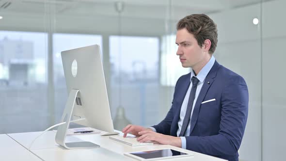 Focused Young Businessman Working on Desk Top in Office 