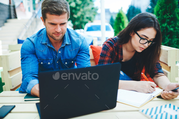 positive hipster guys cooperating on learning course work project via devices