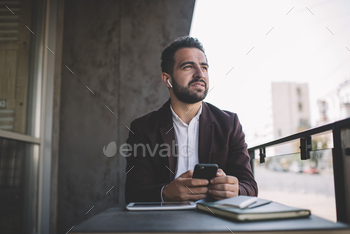 confident businessman using smartphone for chatting and listening audiobook