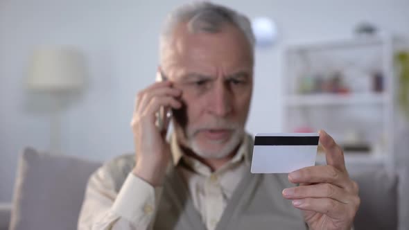 Annoyed Old Man Talking by Cellphone With Bank Support Service About Credit Card