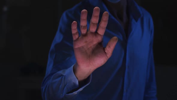 Midsection of caucasian man in dark room using virtual digital interface with hand outstretched