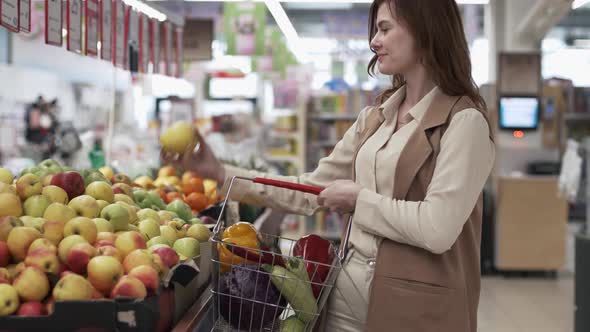 Healthy Eating, Pretty Housewife with Grocery Basket Selects on the Shelves of the Supermarket Eco
