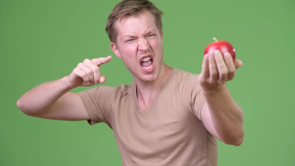 Young Handsome Scandinavian Man Holding Apple and Giving Thumbs Up