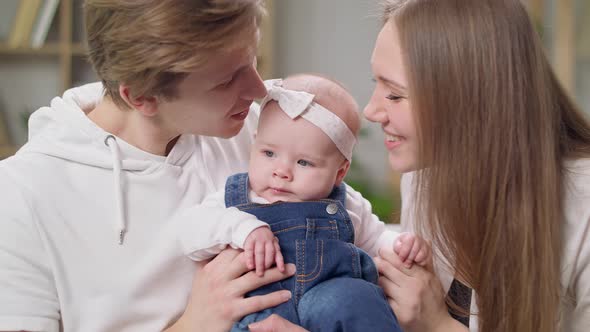 Dad and Mom Kiss a Little Daughter at the Same Time