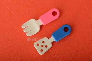 Toy rubber scraper and fork isolated on a red background.