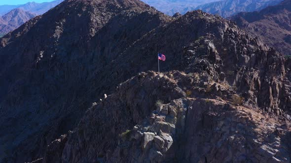 Aerial Shot of American Flag on top of Mountain with Mountain Background