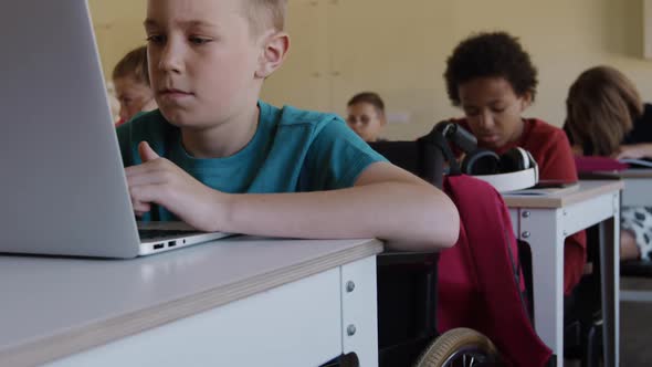 Physically challenged boy using laptop in the class