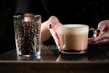 Female Barista's Hand Holding Rich Mocha Coffee in a Glass Cup.