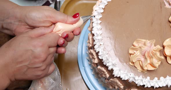 Confectioner Woman is Pouring Cream on Sponge Cake Using Pastry Bag Closeup View