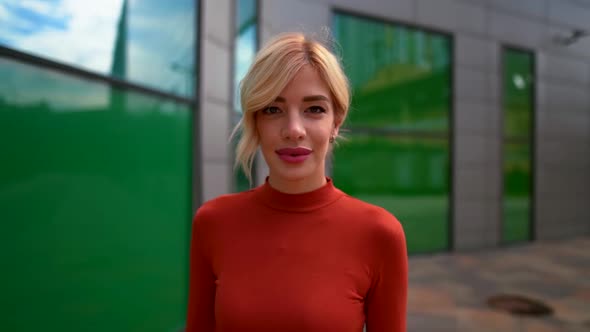 Portrait of a Blonde Woman in Red Clothes and with Bright Lipstick on Her Lips Against the