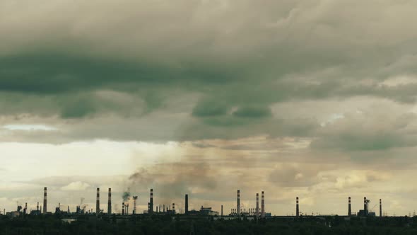 Cloudy sky with clouds over an industrial plant with smoking chimneys, time lapse.