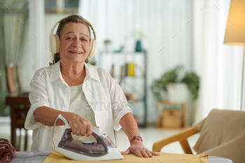Woman Listening to Audiobook when Ironing