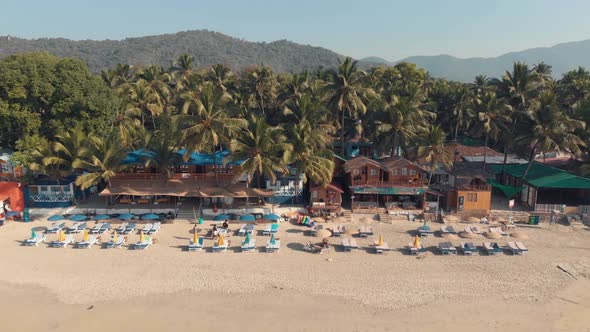 Palolem Beach resort shacks and resting chairs near the coastline in exotic setting