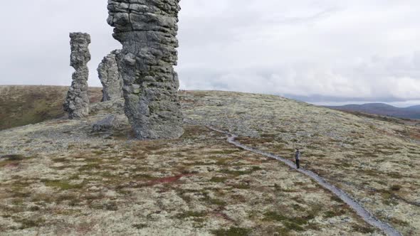 A man looking very small near giant stone pillars, Manpupuner