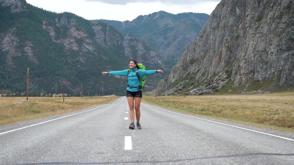 Happy Female Tourist With Backpack Is Turning On Place In Mountains Background