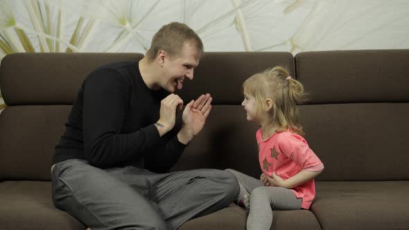 Father and Little Daughter Laughing, Playing Together on Sofa. Leisure Game