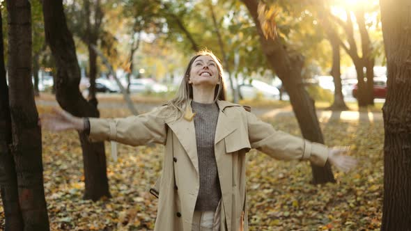 Happy Woman Throwing Leaves in Autumn in Slow Motion Smiling