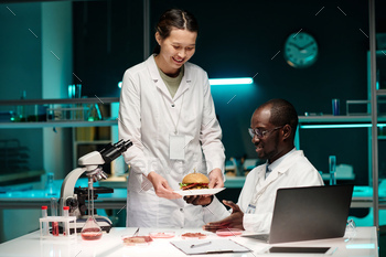 Biracial Scientists Looking at Hamburger with Synthetic Meat