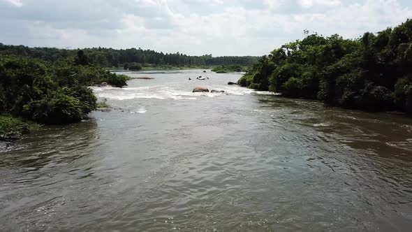 Aerial view of drone zooming away from rafting boats going down the Nile River in Jinja, Uganda, Afr