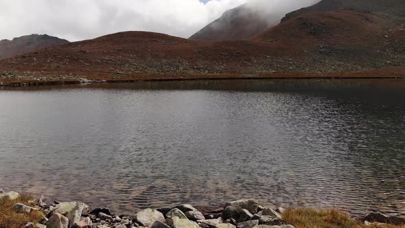 Aerial View of Flight Along the Shore of an Alpine Lake with Crystal Clear Drinking Water