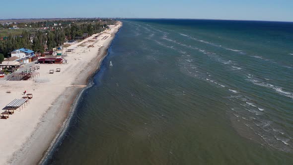 Beautiful flight in summer over the beach. People are resting near the sea. Houses for tourists.