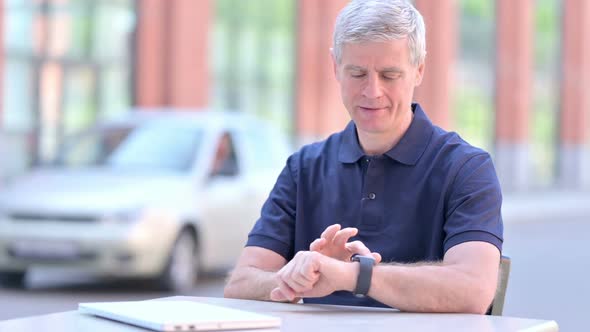 Outdoor Ambitious Middle Aged Businessman Using Smartwatch