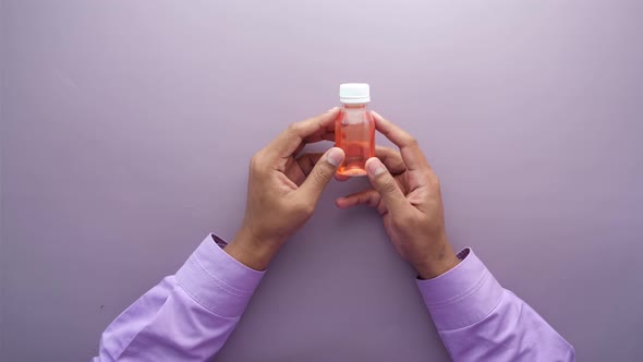 Holding Bottle with Liquid Medicine on Purple Background