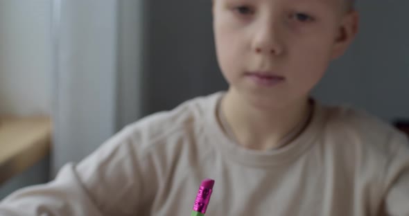 Close Up Front Portrait of Boy Looking at Pencil Ready To Draw Indoors Natural Light