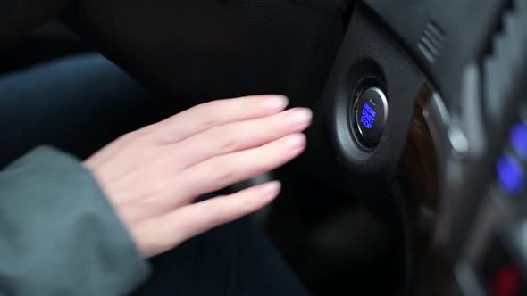 hand of a girl who presses the car engine start button