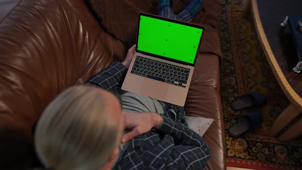 High Angle View Chromakey Laptop on Lap of Cheerful Caucasian Man Laughing Out Loud Watching Online