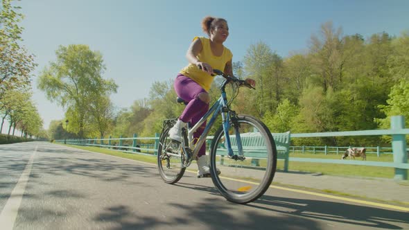 Joyful Lovely African Woman on Bicycle Riding on Park Alley