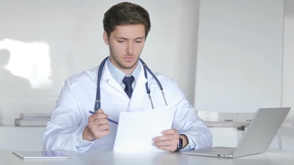 Young Doctor Reading Medical Report Doing Paperwork