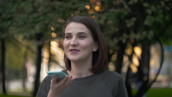 Happy Girl Using a Smart Phone Voice Recognition Audio Message Function on Line Walking on a Street