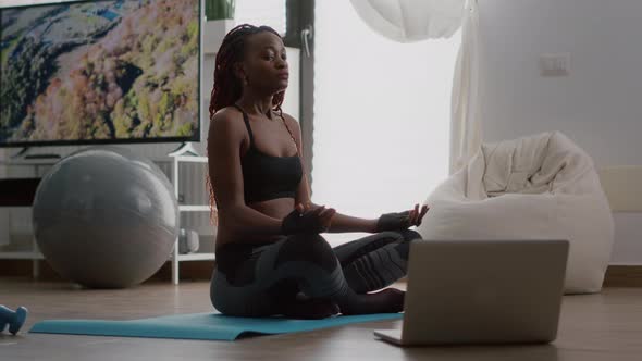 Slim Black Woman Sitting in Lotus Pose on Yoga Map with Closed Eyes