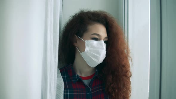 A Woman Is Taking Off Her Face Mask While Being Next To the Window