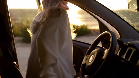 Blonde Woman Getting Into Car and Startting Car on the Coast During Golden Hour