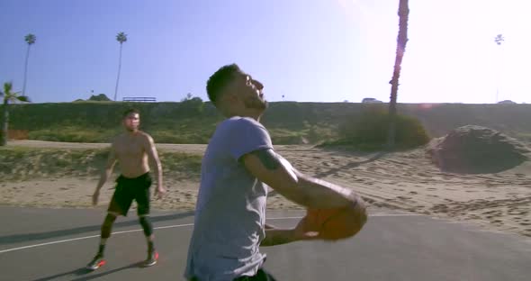 A man does a slam dunk while playing one-on-one basketball hoops on a beach court