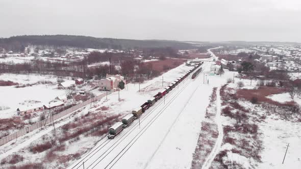 Railway station with railroad tracks and freight train in winter