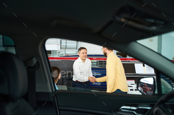 e car dealership, the buyer’s wife is sitting nearby