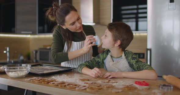 Mom Wipes Flour From Her Son's Face in the Kitchen