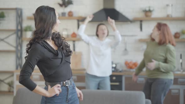 Beautiful Young Slim Woman Looking Back at Dancing Friends and Walking To Kitchen