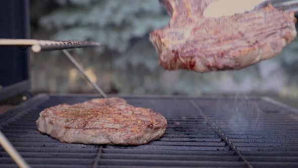 Side view of juicy steaks sizzling and being flipped in hot flames.