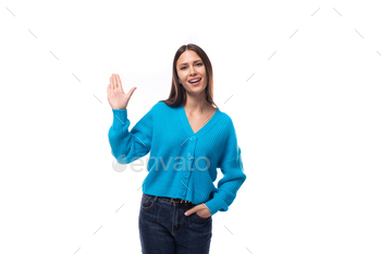 young charming brunette lady dressed in a blue V-neck sweater actively jests on a white background