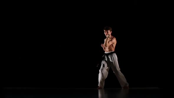 Man Training Taekwondo or Karate Jumping, High Kick and Fist Punch Isolated on Black Background