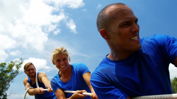 Fit people playing tug of war during obstacle training course 4k