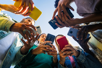 Young group of people using mobile phone device standing in circle outdoors